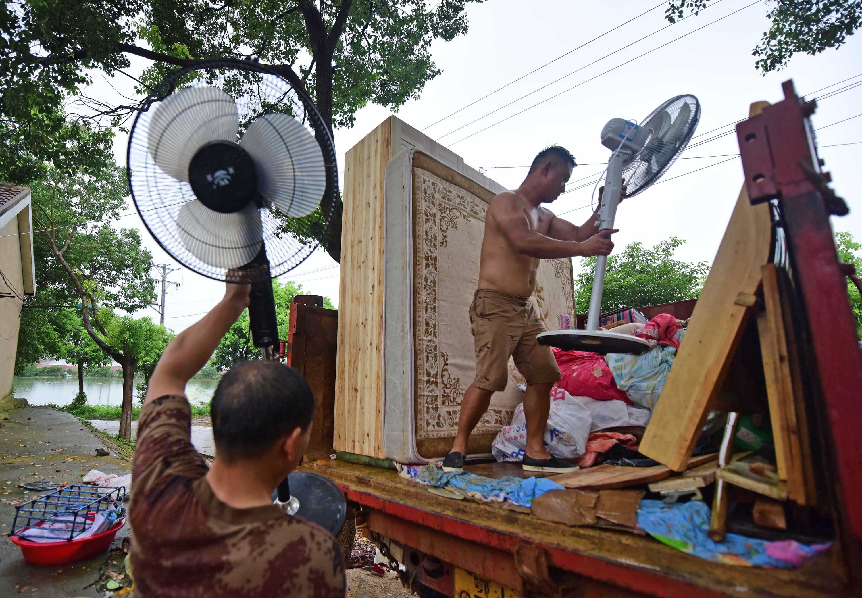 7月13日，牛山湖渔场职工在往车上搬家具，准备撤离。新华社记者 程敏 摄