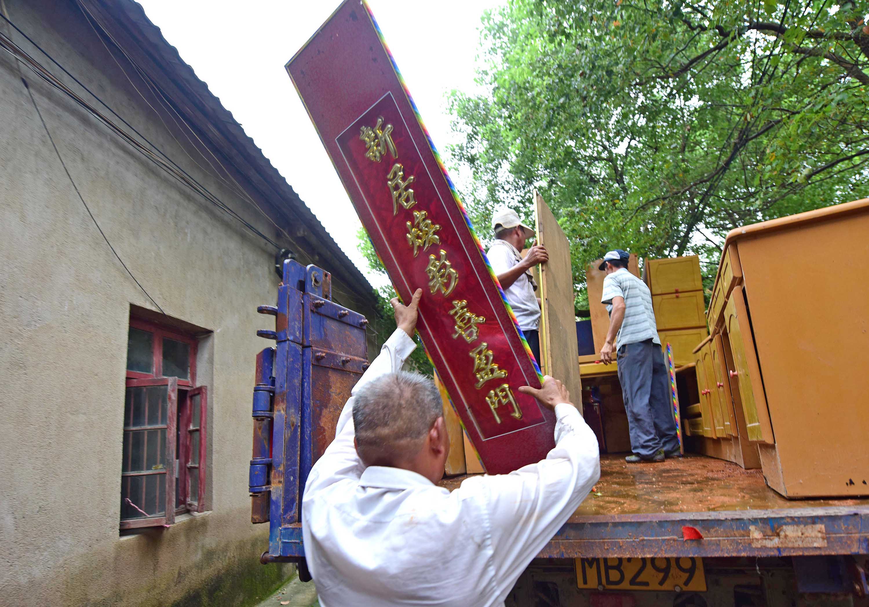 7月13日，牛山湖渔场职工在往车上搬家具，准备撤离。新华社记者 程敏 摄