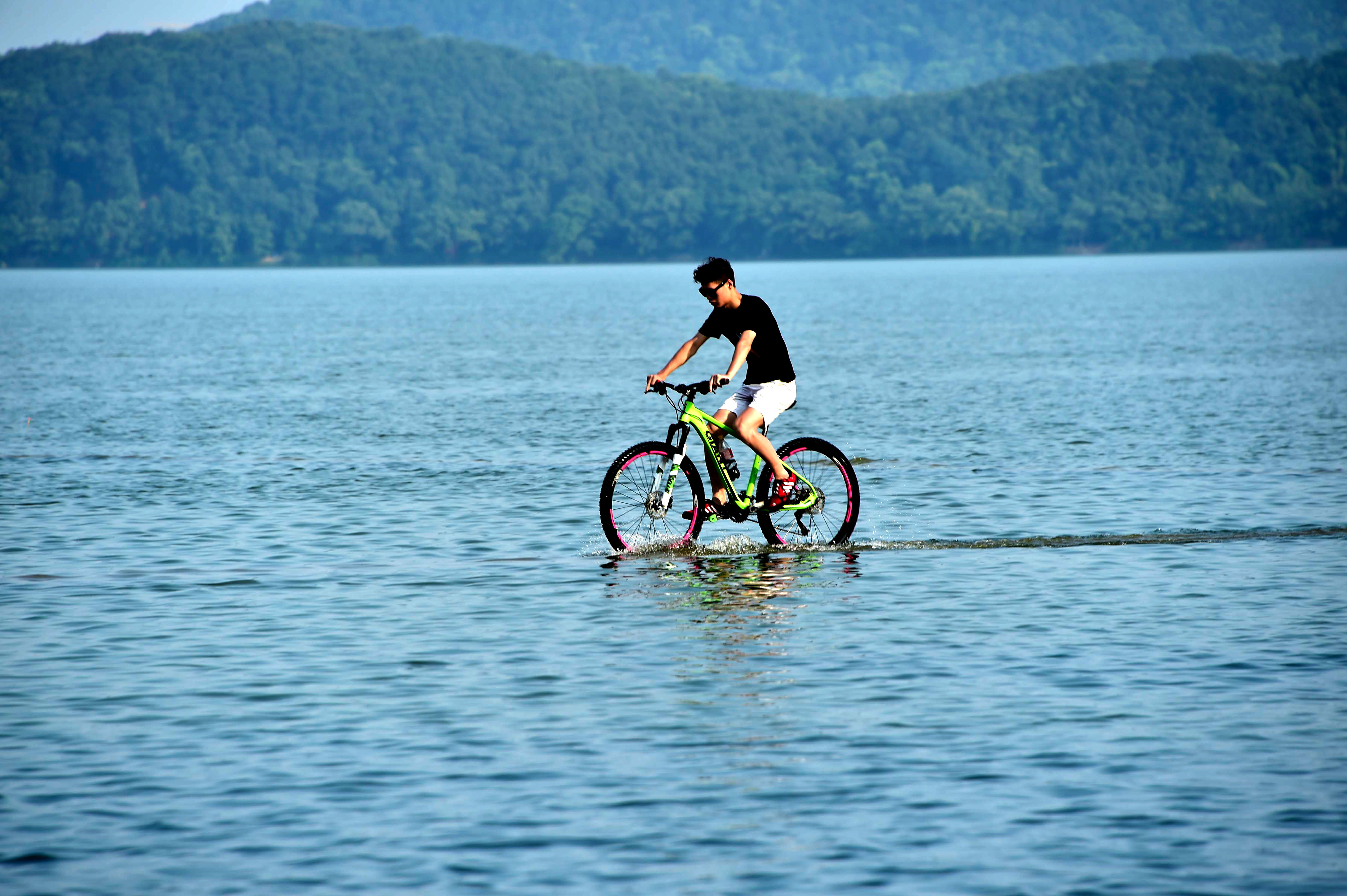 7月8日,一名市民在武汉市东湖风景区的天然浴场的走道上骑自行车.