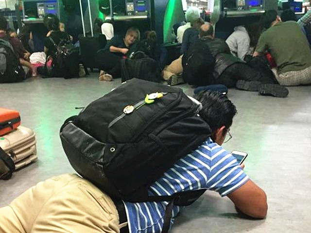 8月14日，纽约肯尼迪机场，乘客在警方的要求下，趴伏在地面上。（图片来源：新华/美联）