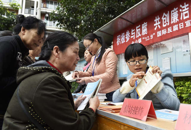 2015年12月8日，在福建省福州市仓山区仓山镇先锋村，纪检监察干部（右）向居民介绍信访举报联系卡使用方法。新华社记者 宋为伟