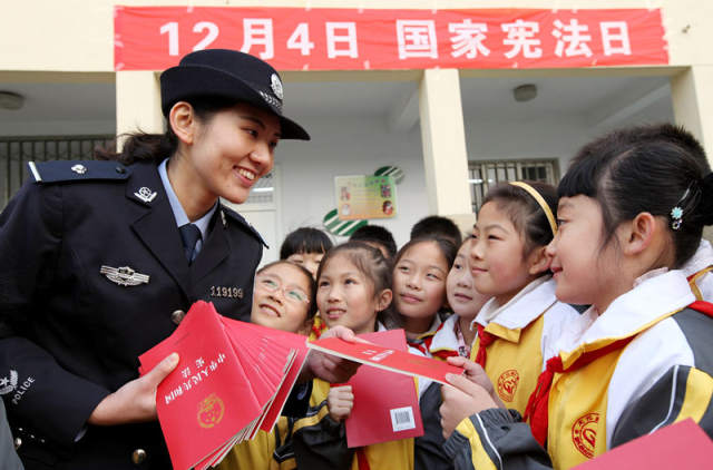 2014年12月3日，民警在山东省枣庄市文化路小学“国家宪法日”系列活动中向学生们赠送《宪法》单行本。新华社发（孙中喆）