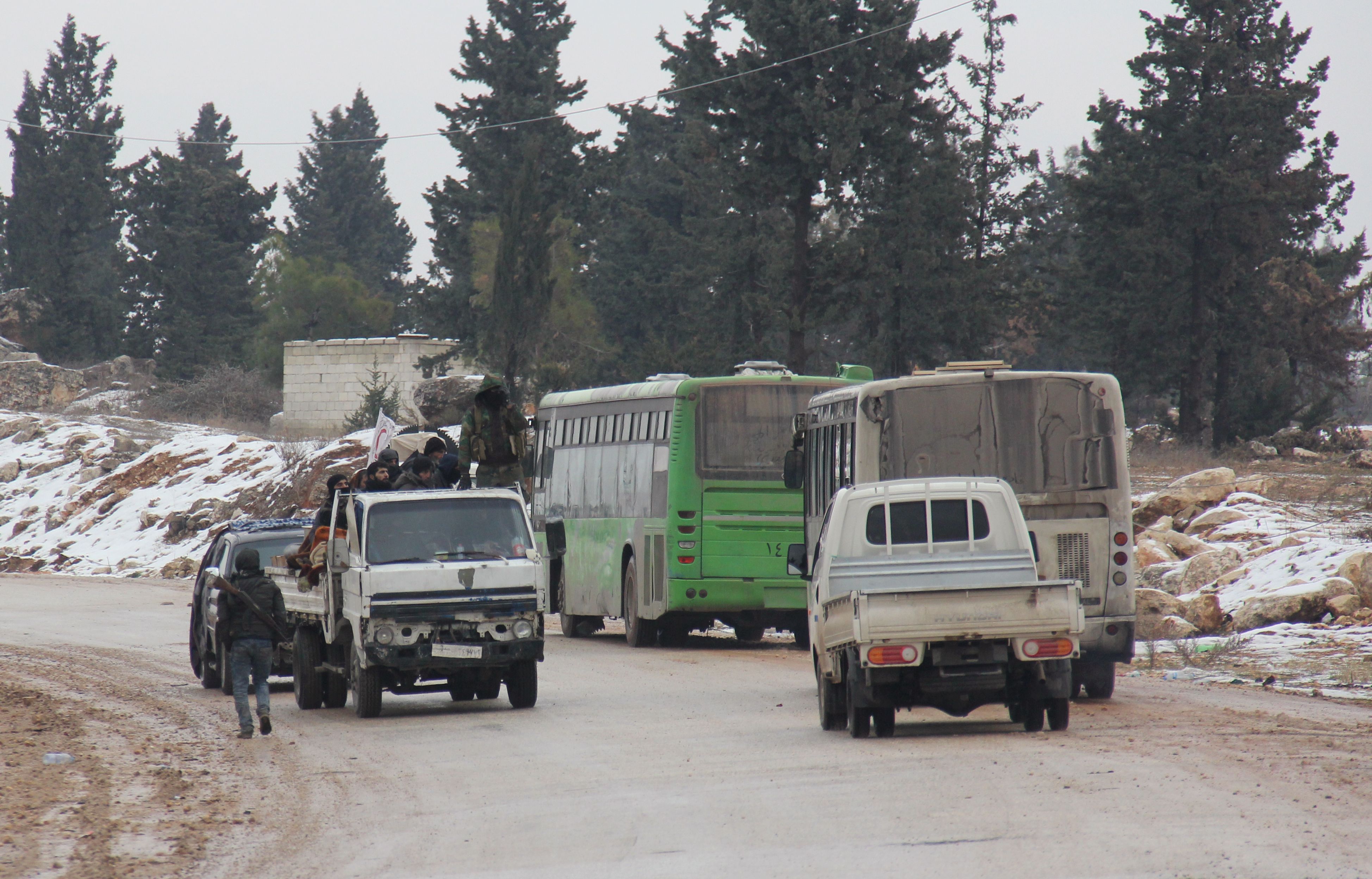 2016年12月22日，载有反政府武装人员的大巴车（右侧）驶离阿勒颇。（新华社/法新）。