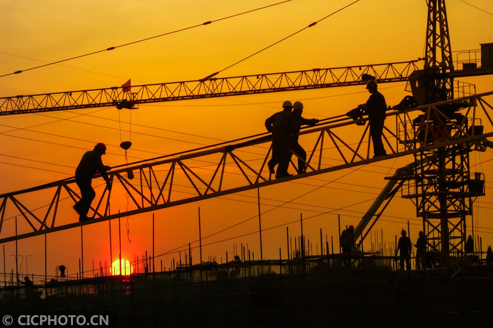 2007年4月4日,江苏省海安县一房产建设工地上,工人们在夕阳下工作.