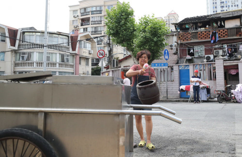 的李才英在演示卫生间改造前每天在居民区外倒马桶的场景(7月18日摄)