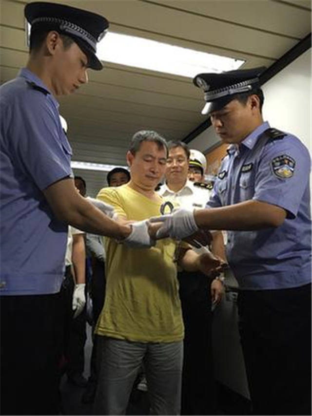 嫌疑人黄某被戴上手铐.蔡岩红摄