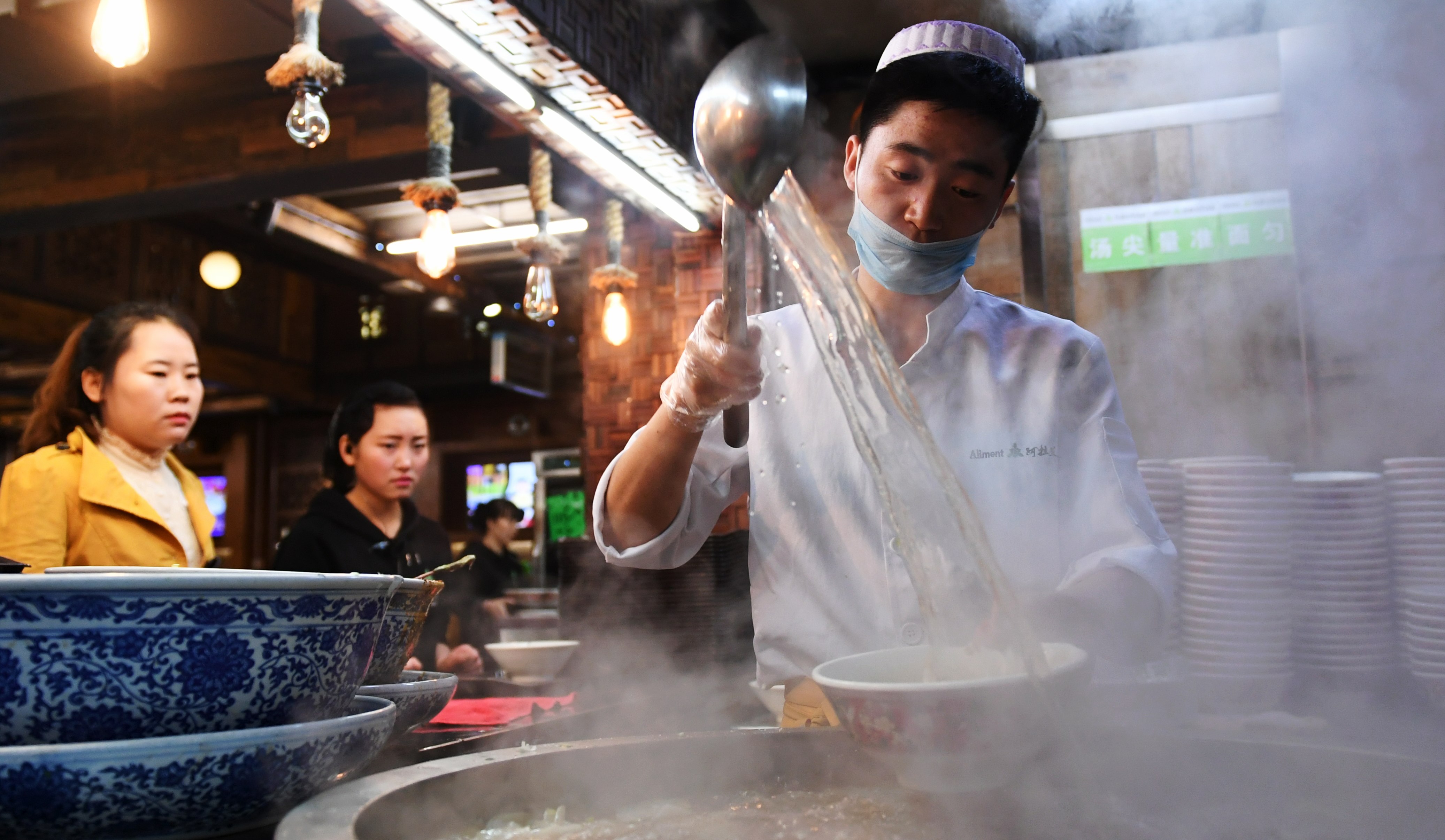4月12日,在兰州市城关区阿拉兰牛肉面主题餐厅,拉面师傅在给牛肉面碗