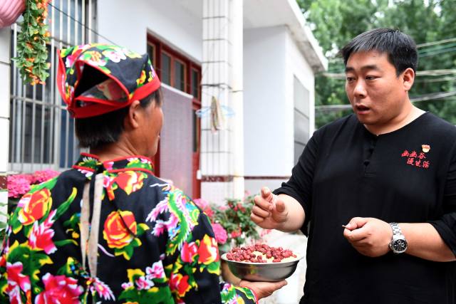 6月13日,淄博市博山区中郝峪村"致富能人"赵胜建在向村民了解农家乐