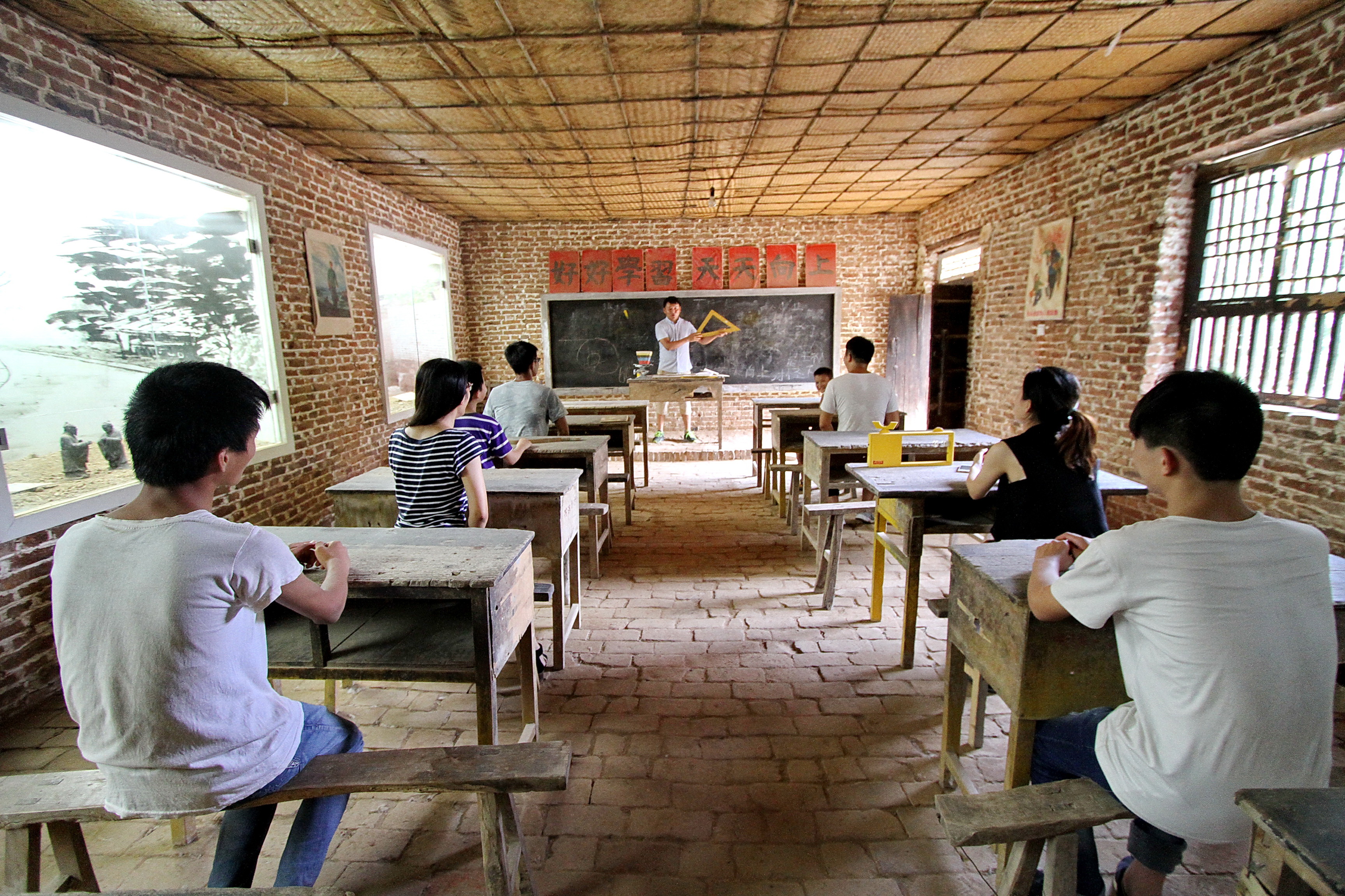 7月19日,游客在河北省馆陶县教育小镇体验20世纪80年代教室的上课情景