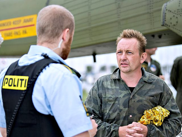 8月11日，丹麦首都哥本哈根以南的德拉厄港，一名警察对马德森（右）进行问询。（新华/路透）