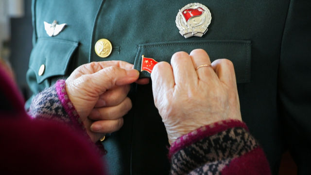 "兵妈妈"王秀兰为"好八连"官兵佩戴国旗徽章(关锁胜摄)70年的峥嵘岁月