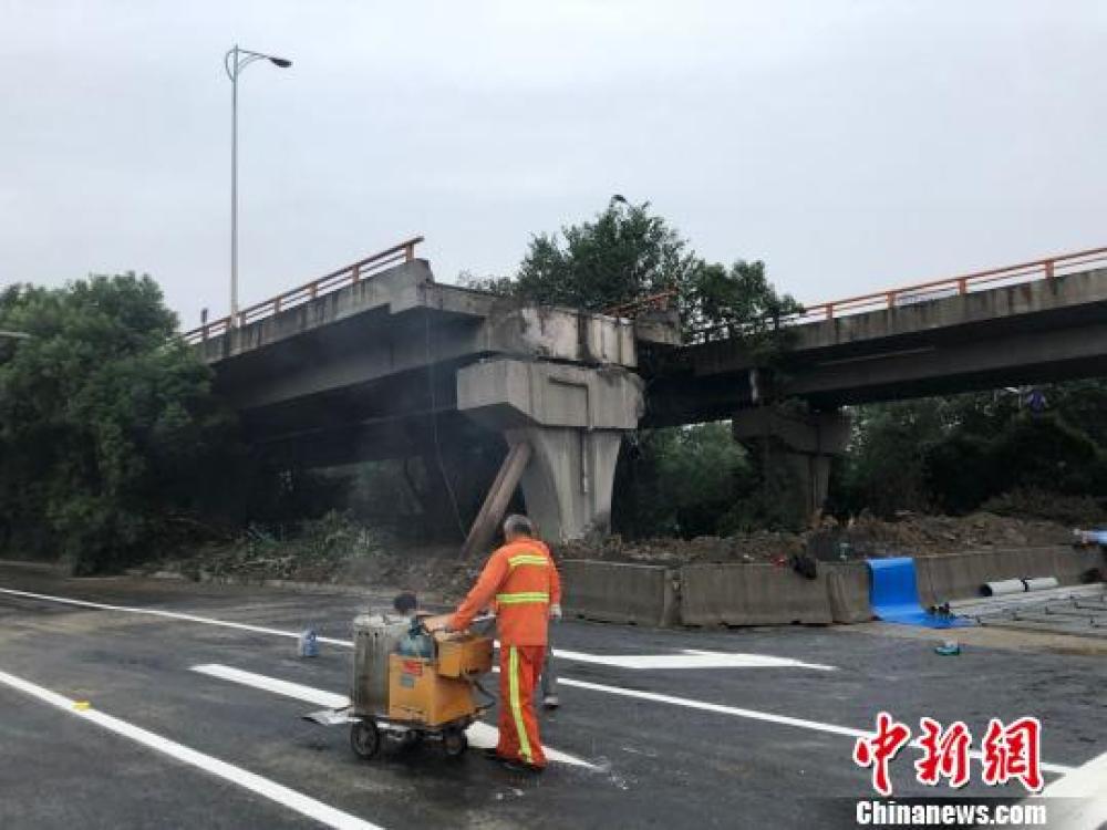 ↑工作人员给事发路段的地面喷上白色的交通标线。孙权 摄