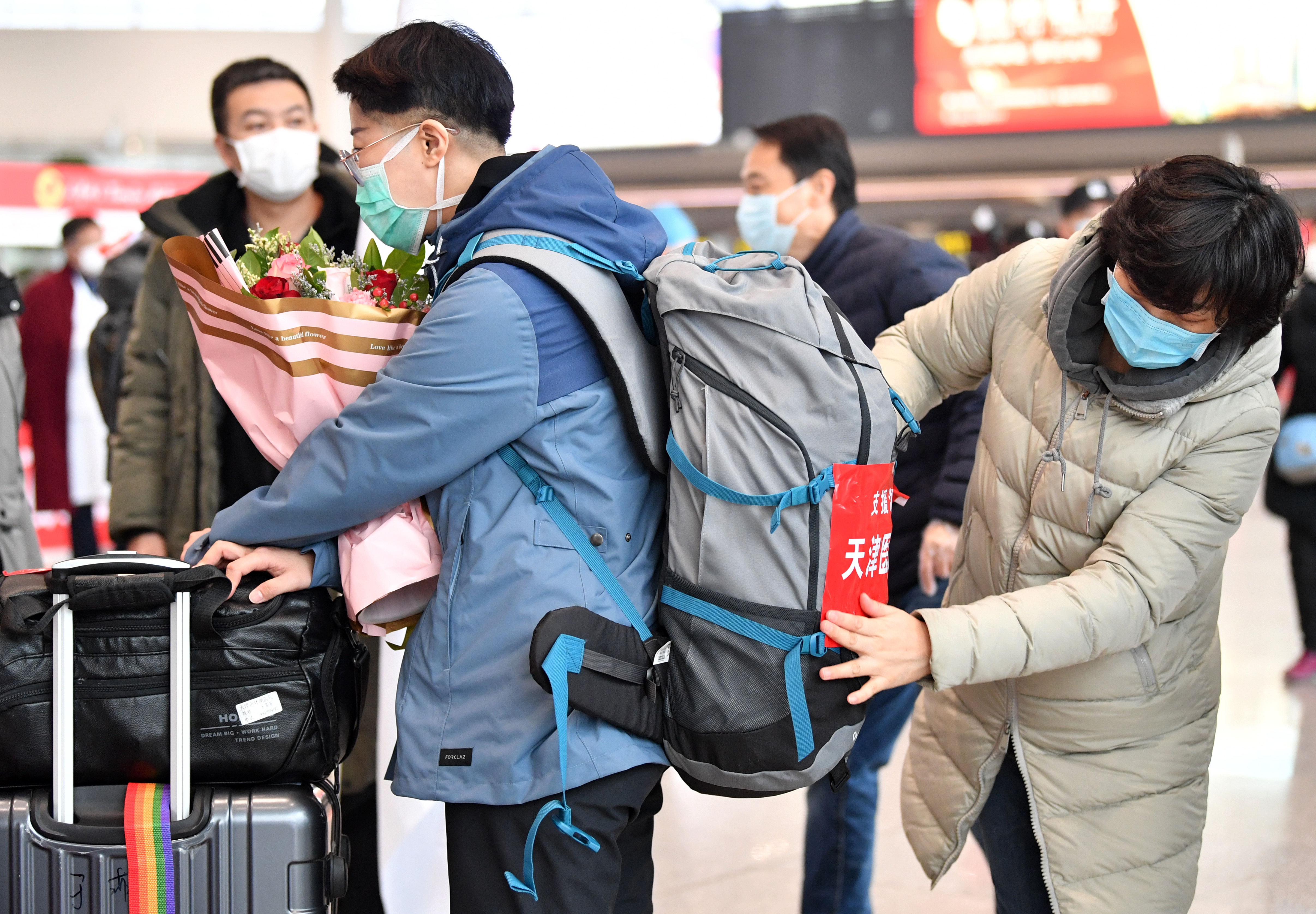 2月20日,送行人员在天津滨海国际机场帮医疗队员张贴标识牌.