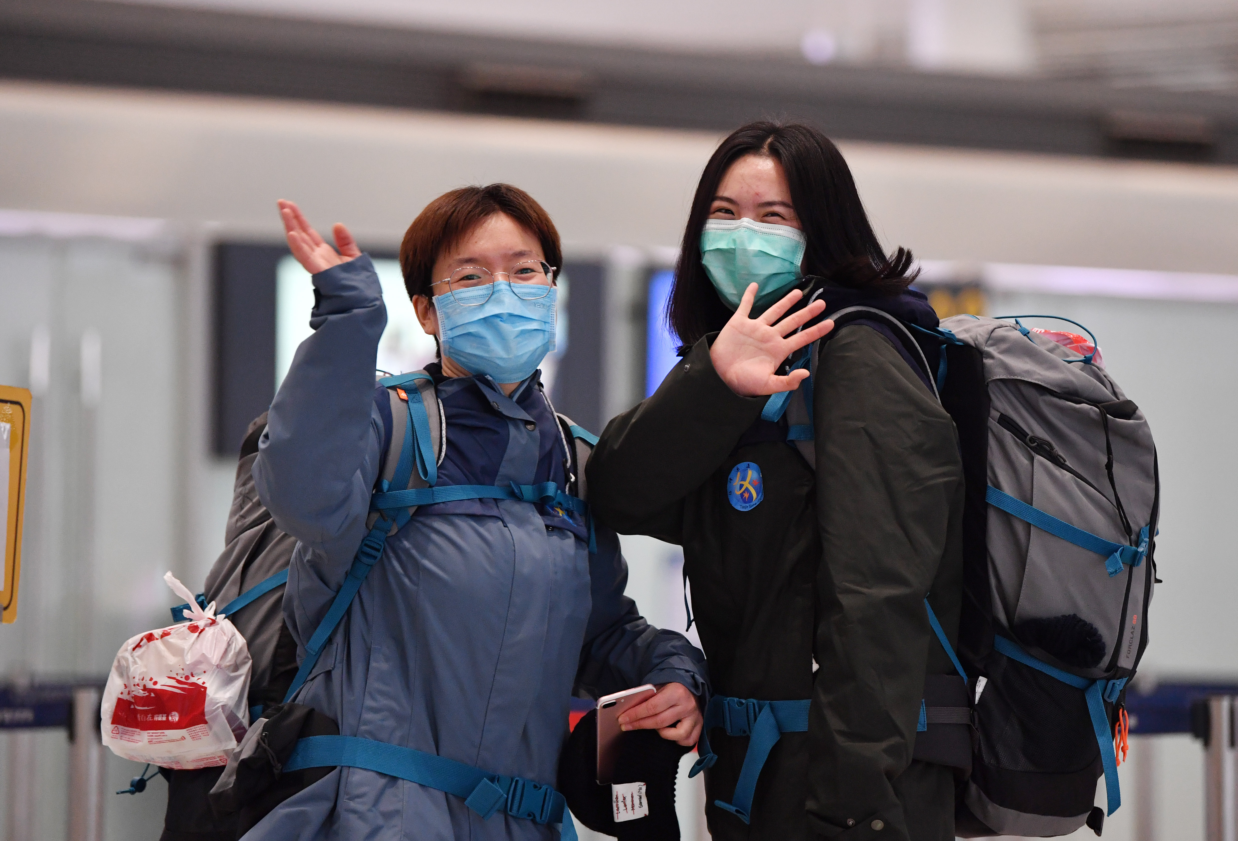 2月20日,医疗队员在天津滨海国际机场和送行人员挥手告别