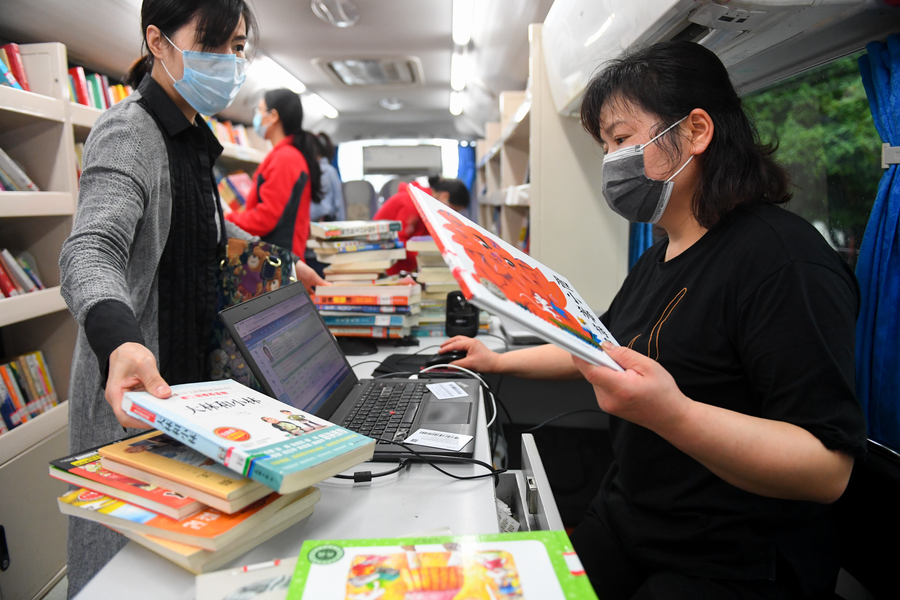 3月26日,在长沙岳麓区石岭塘社区,市民在流动图书馆里办理借书.