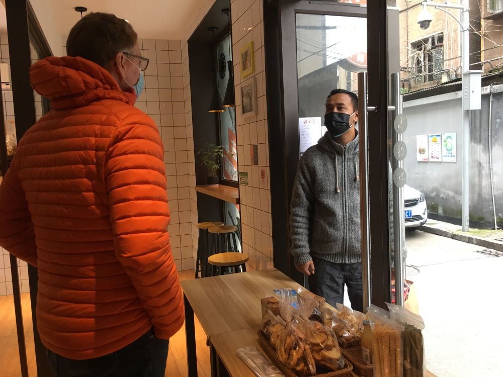 乌韦在面包店内与一位来买面包的尼泊尔顾客交流。新华社记者 蔡潇潇 摄