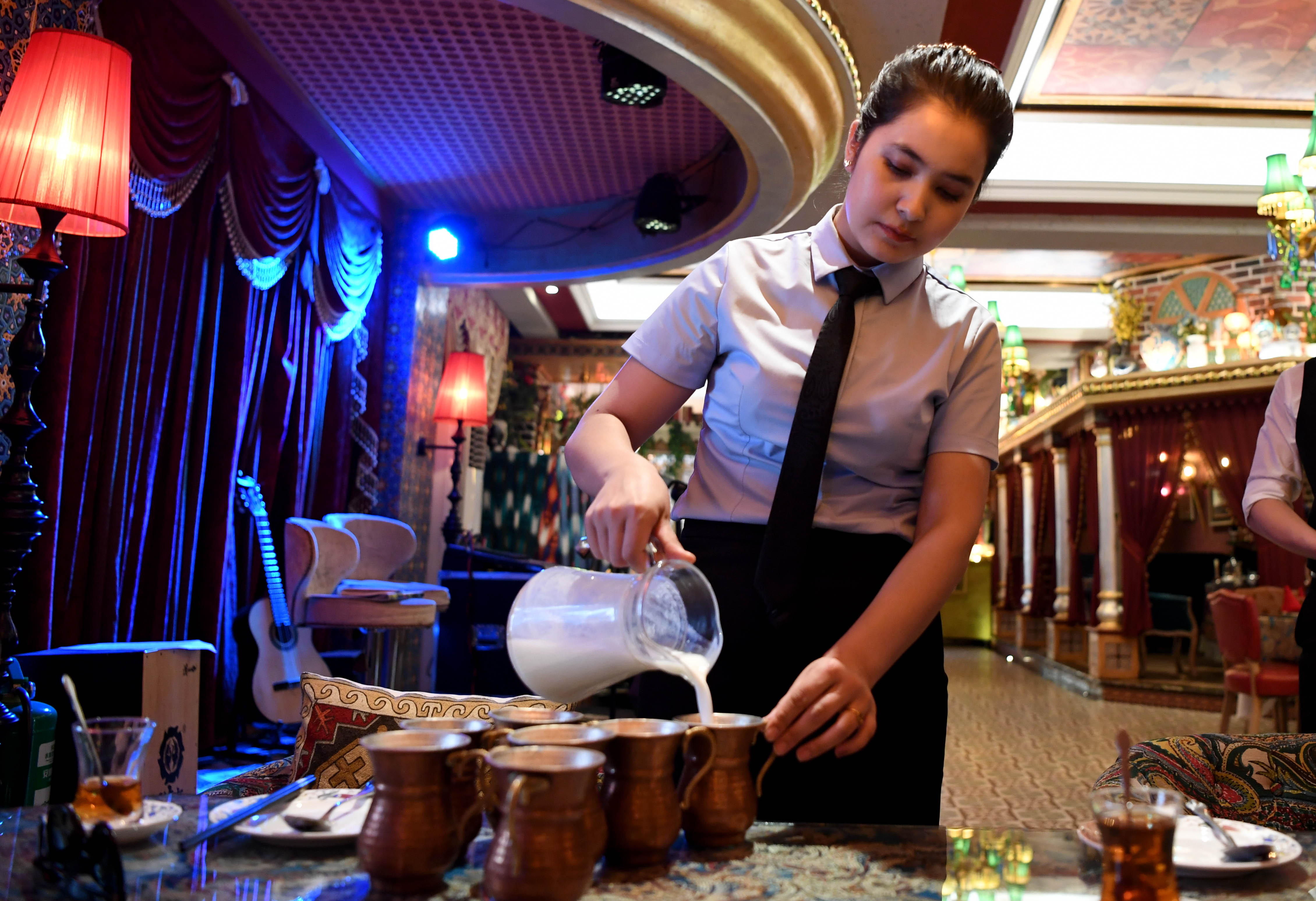 5月27日,一名服务员在新疆和田市团城的鸽子巷一家餐厅工作