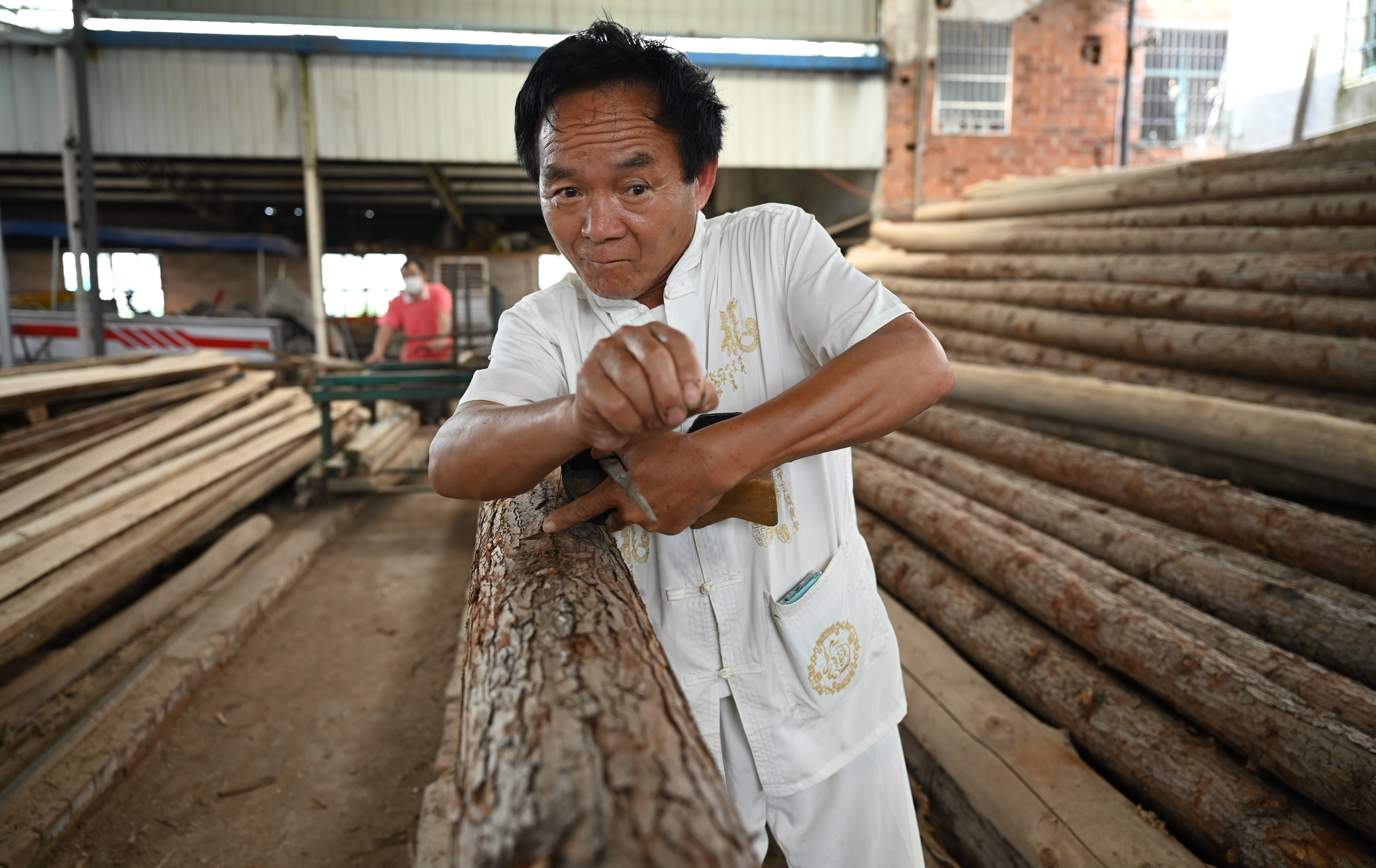 汨罗市屈子祠镇九子龙屈原龙舟厂内,许桂生正手持墨斗在木材上弹墨线