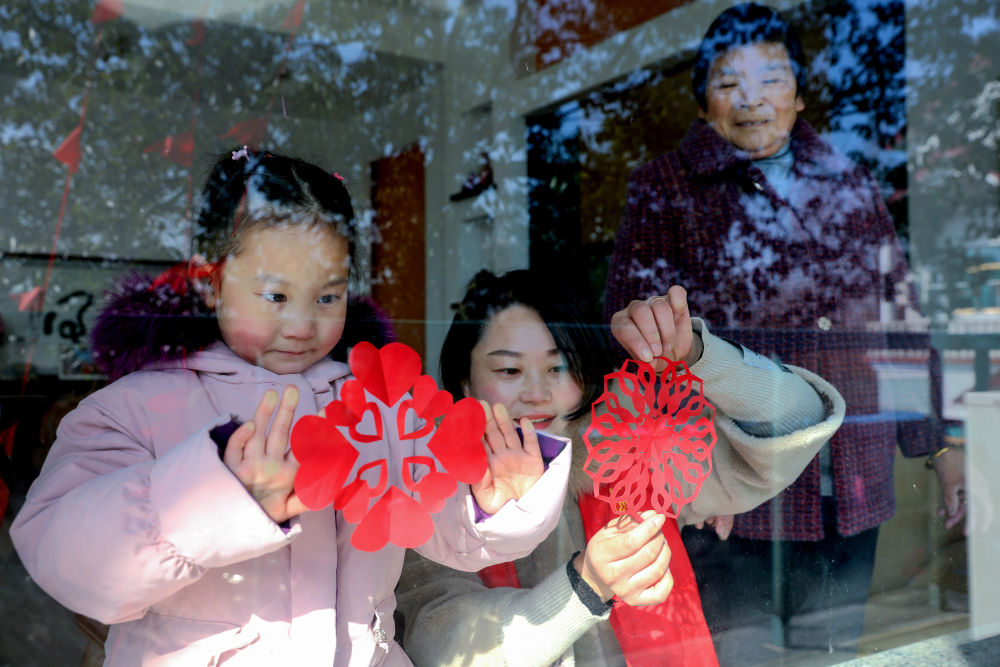 12月30日,小浦镇村民和孩子们一起贴窗花 .