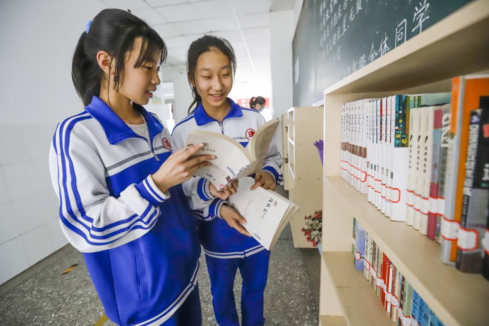 4月22日,河北唐山遵化市第三中学的学生在教学楼走廊图书架旁交流