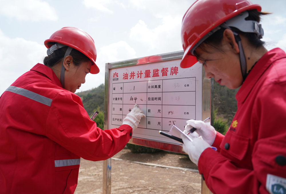 4月26日,女子采油站女工韩慧(左),张美娟在抽油机旁填写计量牌.
