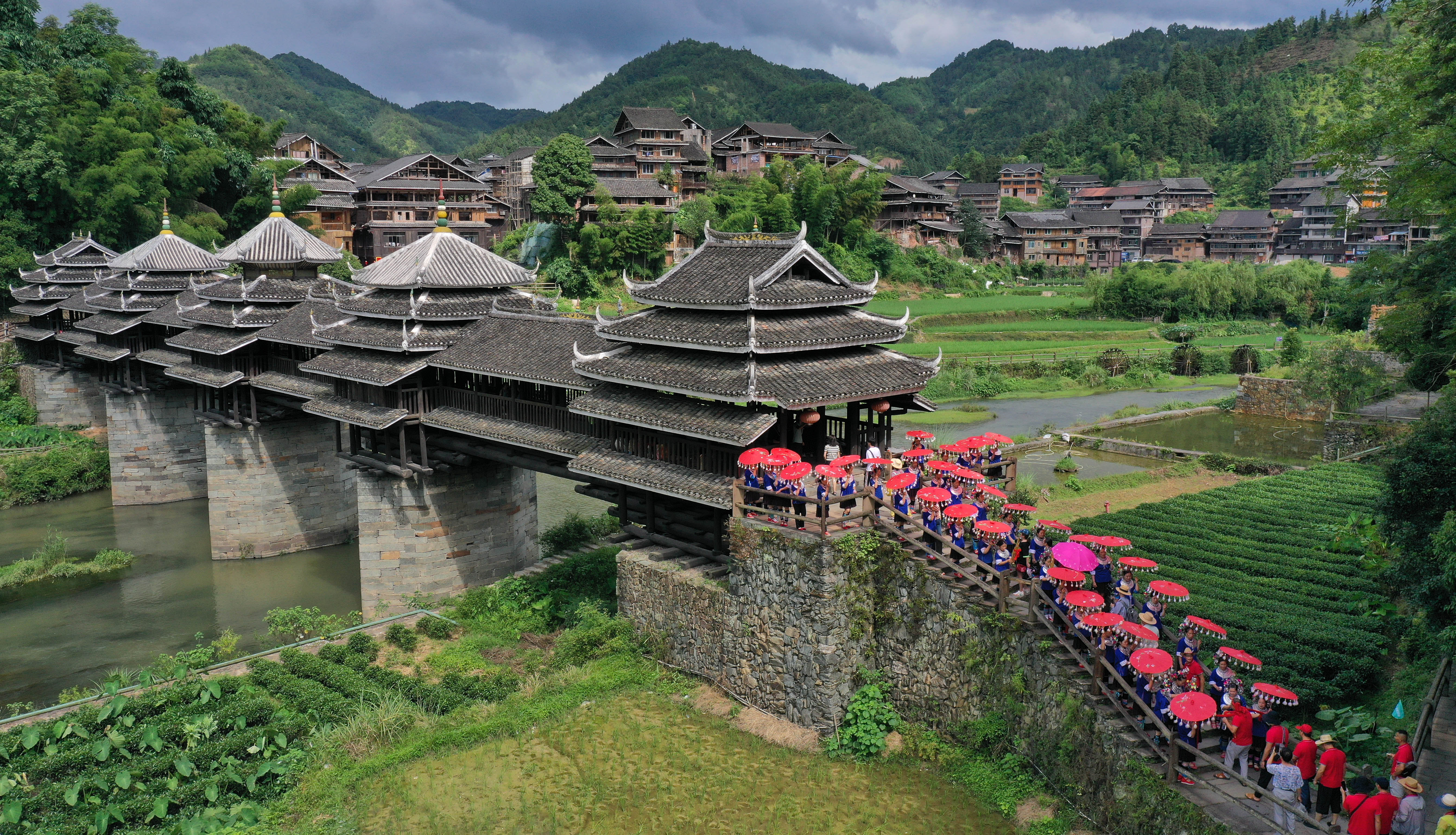 7月8日,在广西三江县程阳八寨,村民在风雨桥头迎接游客(无人机