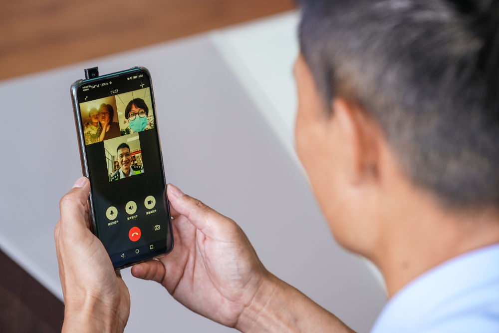 工作间隙,许映宏通过手机与妻子黄滢(右上),孩子视频聊天(7月31日摄