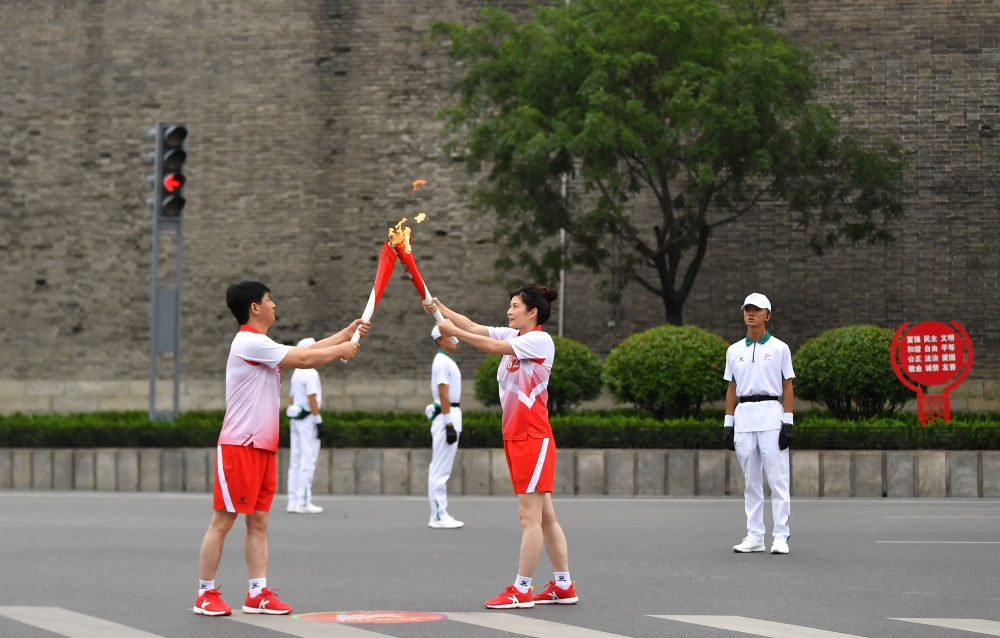 8月16日,火炬手刘楠(前右)和凌国强(前左)在火炬传递中.